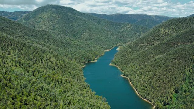 Profile view of Snowy river passing through hills near Mount Kosciuszko National Park, Australia. Drone shot.