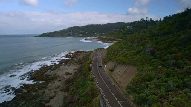 Black SUV car drives along beautiful Australian Great Ocean Road near Wye River, Victoria