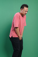 Young man with hands holding his crotch isolated on green background. Sick man prostate cancer...