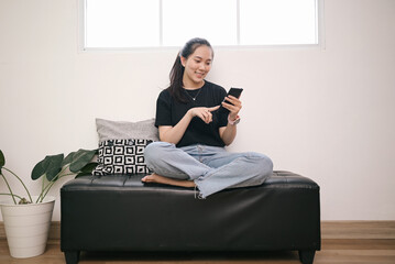 Young Asian female enjoy scrolling social media on smartphone at home