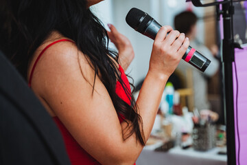 A music artist in a red dress passionately singing into a microphone