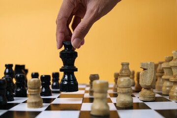 Hand holds king chess in front of pawn chess on chessboard for business strategy and leadership...