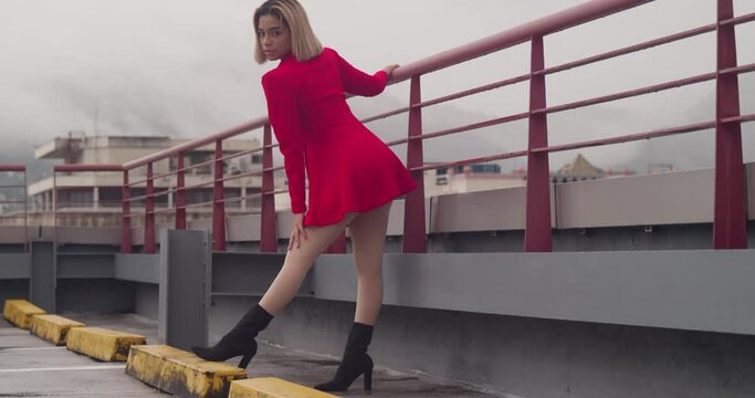 At a Port of Spain rooftop, a young Hispanic girl in a red dress stands against the backdrop of tall buildings in Trinidad.