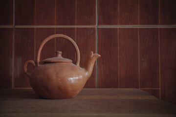 Earthenware kettle on wooden table background.