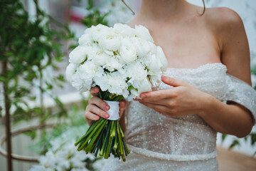 Bride in wedding dress with white flower bouquet, looking happy