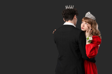 Young girl hugging her prom date and crying on black background