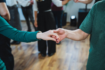 Group in formal wear holding hands, dancing at event in woodpaneled room