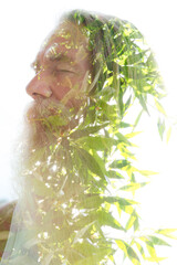 A portrait of a bearded man merging into young tree leaves in a double exposure