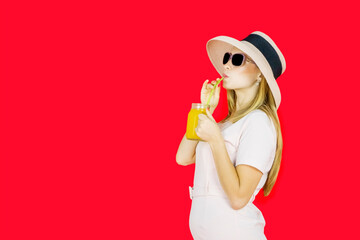 Fashionable woman wearing sunglasses and hat drinking an orange juice