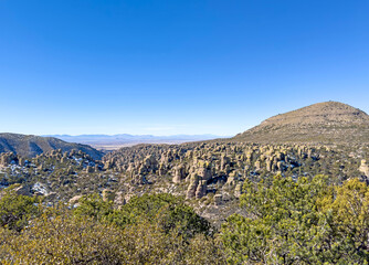 A clear blue sky above Chiricahua National Monument with its rock formations and green forest....