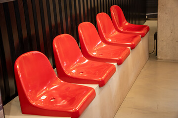 A row of red, numbered grandstand seats, used as visitor chairs