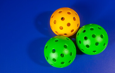 Colorful Pickleball ball in blue background. Pickleball is a new sport that is developing and starting to be popular with the public.