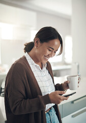 Phone, smile and Asian woman drinking coffee in kitchen at home for breakfast in the morning. Smartphone, tea cup and happy person on social media, internet search and reading email on mobile app