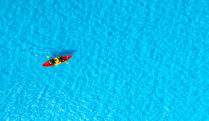 Aerial view of a woman and a young man kayaking on clear blue waters at Andaman Island. She does...