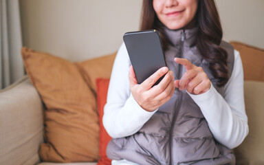Closeup image of a young woman holding and using smart phone at home - 785918906