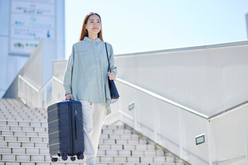 スーツケースを持って階段を下る女性のインバウンド外国人旅行者