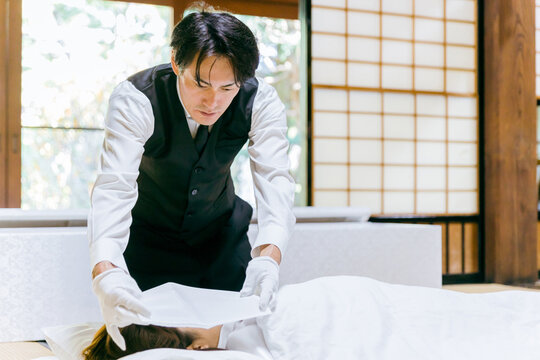 故人に打ち覆い・面布をかける納棺師・セレモニースタッフ・葬祭ディレクターの日本人男性
