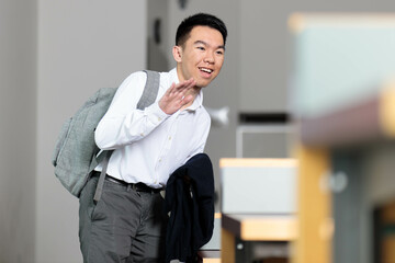 A business student in formal wear walking into a classroom waving hello