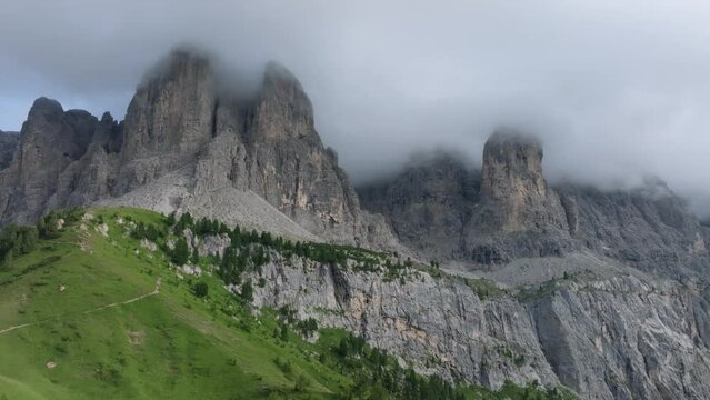 Aerial forward flying drone shot of the rugged peaks in Passo Gardena covered in clouds. The drone ascends and turns right.Dolomites, Trentino, South Tyrol, Italy. LuPa Creative.