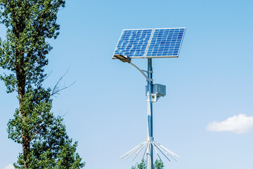 Solar device with street lamp on background of blue sky. Street light powered by solar panel with...