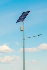 Obraz premium Solar device with street lamp on background of blue sky. Street light powered by solar panel with battery included. Alternative energy from the sun