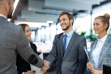 Business partners handshaking over business objects on workplace.
