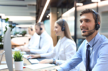 Portrait of call center worker accompanied by his team. Smiling customer support operator at work. - 785936581
