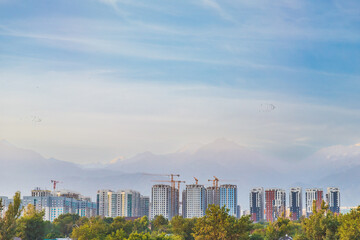 Dense development of the city of Almaty with high-rise residential complexes against the backdrop of mountains in a seismic zone, copy space