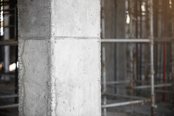 Close-up of Reinforced concrete structural column against the background of scaffolding for pouring concrete floors of a building under construction.