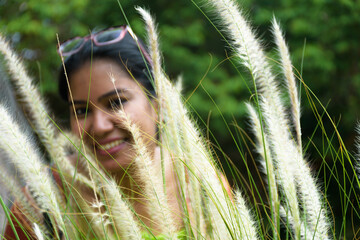 Beautiful young Indian woman behind grass in the grass field Giving the feeling of relaxation,...