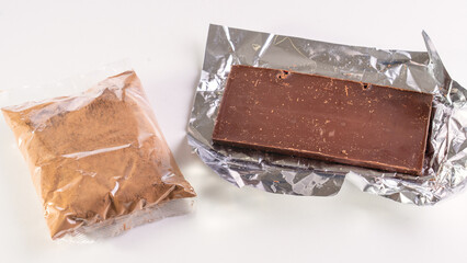 Chocolate bar unfolded in foil sheath. Cocoa and chocolos on white background, concept of price...