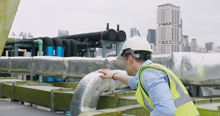 A Engineer man looking inspecting maintenance insulated pipelines valve pump control on the roof at...