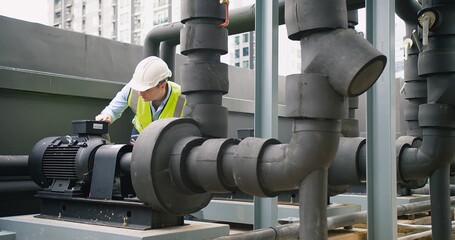 A Engineer man looking inspecting maintenance insulated pipelines valve pump control on the roof at...
