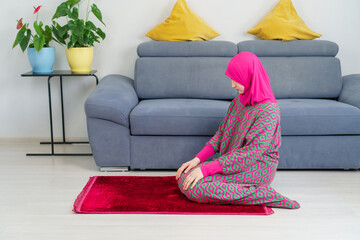 A teenage girl in a modern pink dress for prayer performs salat