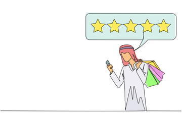 Single one line drawing happy Arabian man holding several shopping bags. The other hand typing on the smartphone gives a 5 star review. Online shopping. Continuous line design graphic illustration