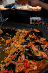 Street food in London, food court on Portobello road Saturday market, fresh prepared colorful paella with rice and sea food big pan, ready to eat