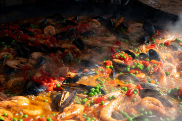 Street food in London, food court on Portobello road Saturday market, fresh prepared colorful paella with rice and sea food big pan, ready to eat