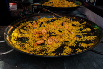 Street food in London, food court on Portobello road Saturday market, fresh prepared colorful paella with rice and sea food big pan, ready to eat