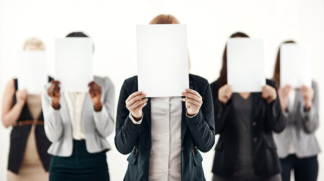 Businesswoman, group and holding message on board in studio for anonymous recruitment of career. Professional, team and female people with blank paper hiding face for marketing as brand ambassador