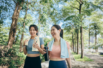 two Asian women engaging in physical activity within an urban park.