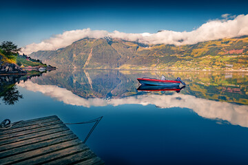 Calm summer view Norwegian fjord with small fishing boat. Stunning summer scene of Lofthus port in...