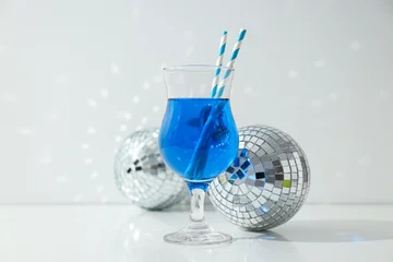Gordijnen Blue cocktail with straws in glass and disco balls on white background © Atlas