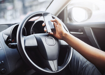 Person, texting and driving with phone on steering wheel with scroll, danger and risk. Road safety, awareness and driver in car with hand on smartphone, distraction and attention with auto insurance