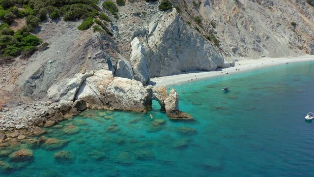 Aerial: Flying over the limestone arch rock formation in Lalaria beach in Skiathos island, Sporades, Greece with turquoise and emerald crystal clear water