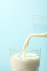 Bottle and glass with milk on blue background, close up
