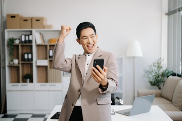 Confident Asian man with a smile standing holding notepad and tablet at the office..