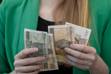 Kobieta przelicza gotówkę w polskiej walucie, banknoty w rękach  - obrazy, fototapety, plakaty