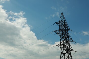 Telephone pole and wires against blue sky with clouds