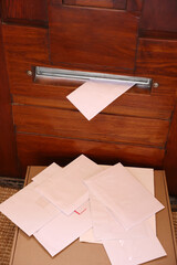 Wooden door with mail slot, many envelopes and cardboard indoors, above view
