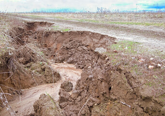 Soil erosion. Destruction of a field dirt road by spring meltwater. The beginning of the formation...